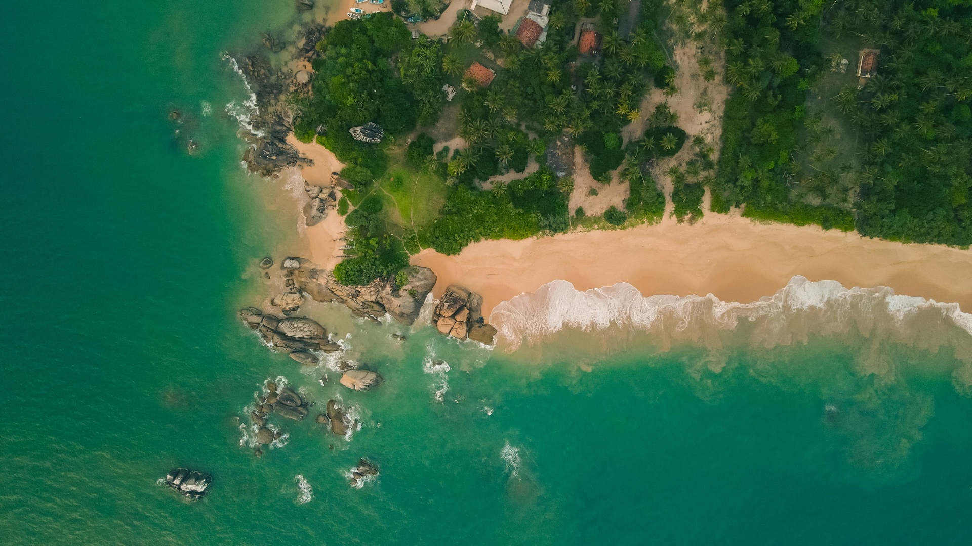 Aerial view of a pristine Sri Lankan beach with turquoise water and golden sand